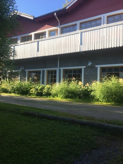 Kermankeitaan punamullattu päärakennus lasitetulta verandalta